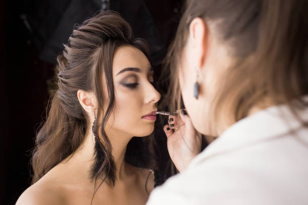 pretty woman make up artist applying makeup to beautiful latina girl - brushing women make up ceremonial makeup imagens e fotografias de stock