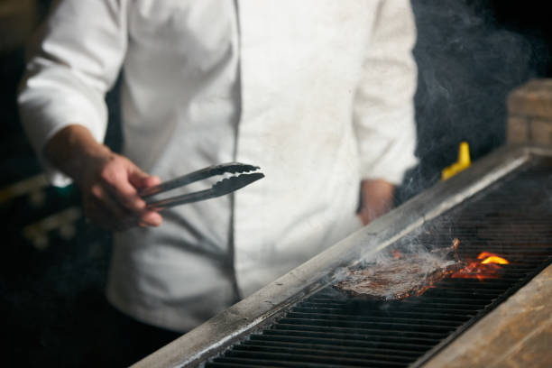 istock Chef cooking beef steak on bbq in restaurant kitchen 944360336