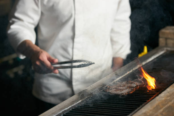 istock Chef cooking beef steak on bbq in restaurant kitchen 944360620