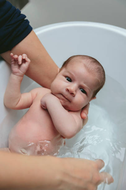 istock Newborn in the bathtub held by her mother 944369202