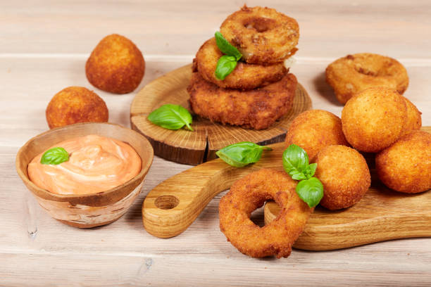 istock Delicious snacks: cheese balls and onion rings with sauce 944372542