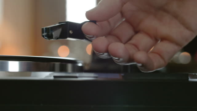 male hands putting a needle on a record.