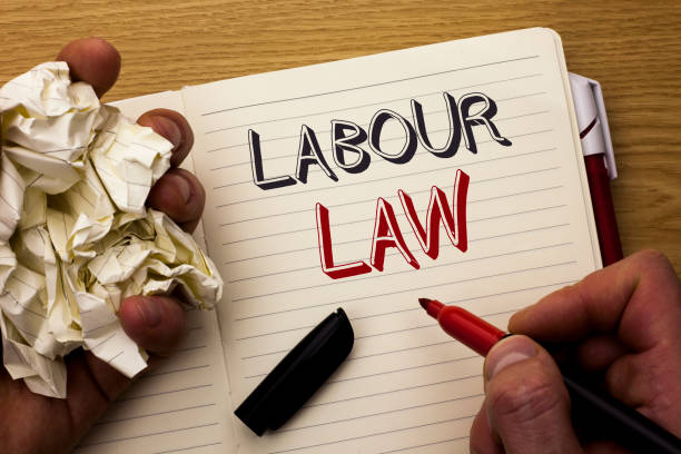 istock Handwriting text Labour Law. Concept meaning Employment Rules Worker Rights Obligations Legislation Union written by Man on Notebook Book Holding Marker on the wooden background Pen next to it. 944385820