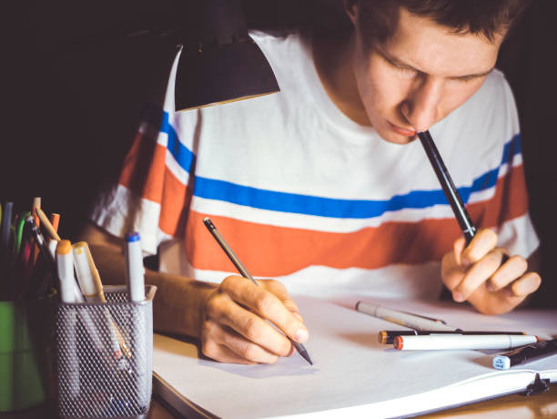 istock young man making a sketch on paper with pencil and markers 944389768