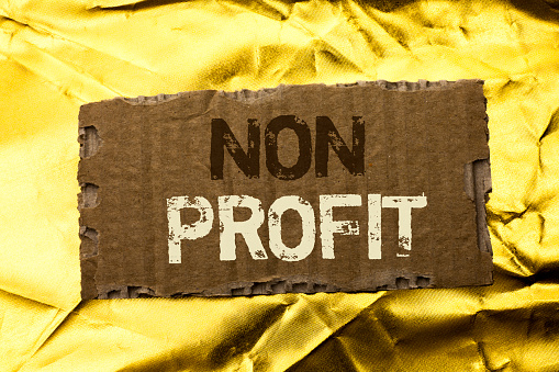 Word writing text Non Profit. Business concept for Charitable Wrothless Philanthropy Aid Unlucrative Profitless written tear Cardboard Piece the Golden textured background.