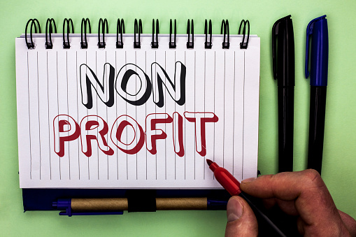 Writing note showing  Non Profit. Business photo showcasing Charitable Wrothless Philanthropy Aid Unlucrative Profitless written by Man Holding Marker Nootbook Book plain background Marker.