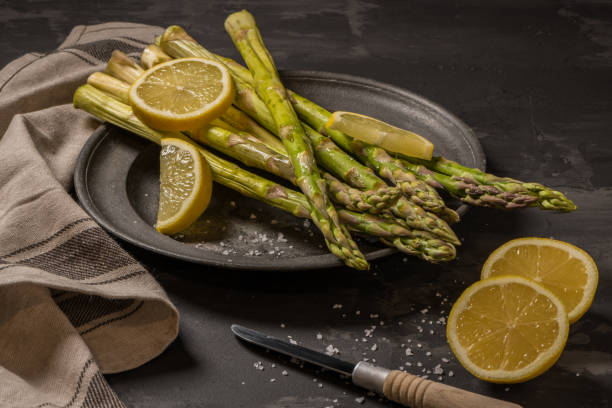 istock Bundle of young raw uncooked organic green asparagus with sliced lemon 944397334