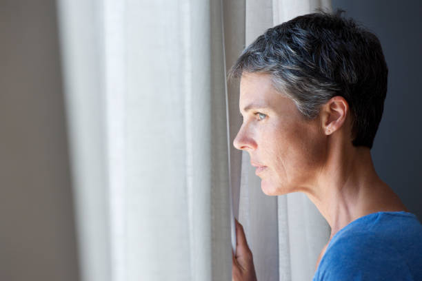 istock older woman looking out window 944398864