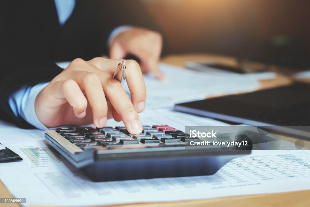 close up hand accountant using calculator with laptop. concept saving finance and accounting Calculator Stock Photo