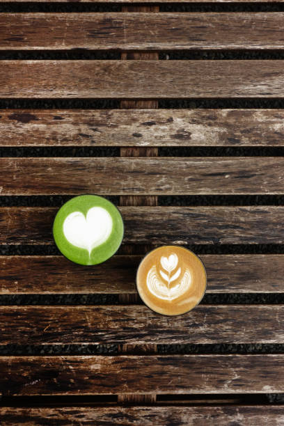 A cup of green tea matcha latte and cup of latte art coffee