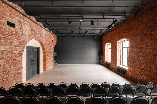 istock Loft style. Hall with black chairs for webinars and conferences. A huge room with large Windows, surrounded by brickwork, and parquet floors. For film and theatre productions 944436964