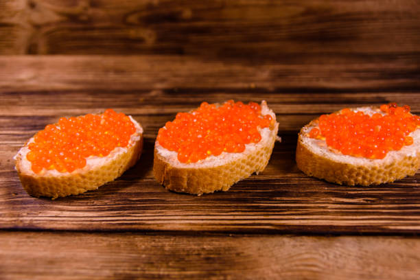 istock Sandwiches with red caviar on wooden table 944447256