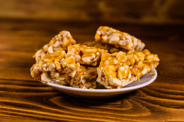 istock Ceramic plate with peanut brittles on wooden table. 944447270