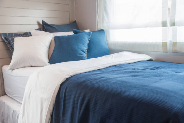 istock Many blue and white bedroom with warm light from window. 944449874