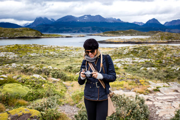attractive woman with black hat looking at camera in her hands and smiling in wild landscape, Ushuaia, Patagonia attractive woman with black hat looking at camera and smiling in beautiful wild landscape, Ushuaia, Patagonia. tierra del fuego archipelago stock pictures, royalty-free photos & images
