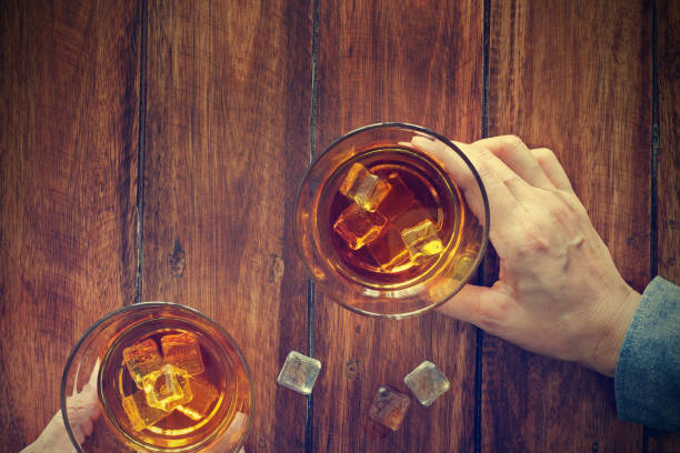 パブのバーカウンターで一緒にウイスキーのウイスキーの2人の男性クリンクグラスのクローズアップは、一緒にアルコール飲料を飲みます - thailand restaurant cocktail bar ストックフォトと画像