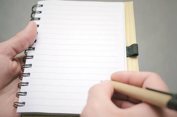Close-up of a man's hand writing on paper at night, hand writing a letter, writing in a diary