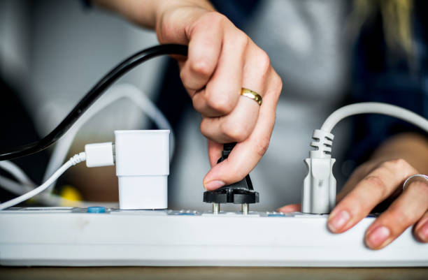 enchufar el cable a la salida de la mujer - enchufe fotografías e imágenes de stock