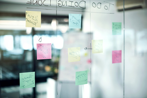 Shot of sticky notes on a glass wall in an empty office room