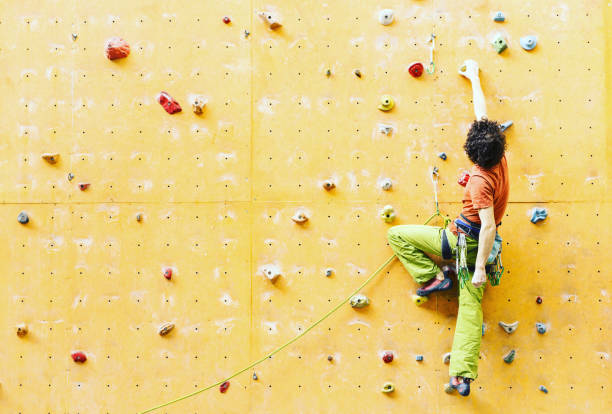 fitness, esportes radicais, bouldering, pessoas e conceito de estilo de vida saudável - jovem exercitar no ginásio de escalada indoor - men on top of climbing mountain - fotografias e filmes do acervo