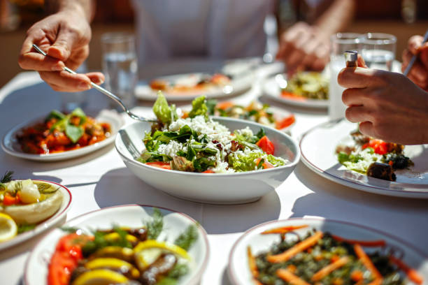 paar beim mittagessen mit frischen salaten und vorspeisen - essen mund benutzen fotos stock-fotos und bilder