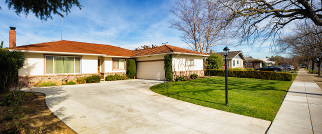 Panoramic view of a house, empty driveway and sidewalk in San Jose California on a sunny day