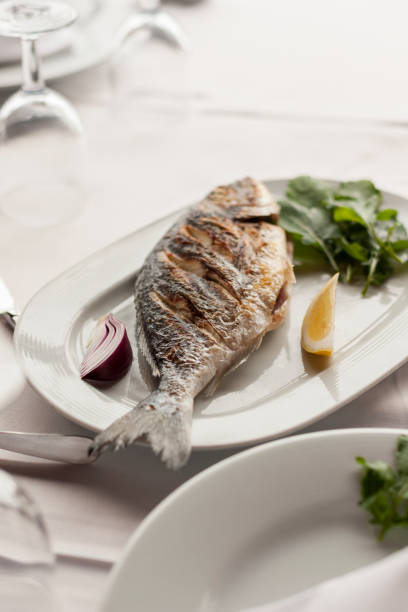 istock Grilled Sea Bream Served on a White Plate with Vegetables 944481426