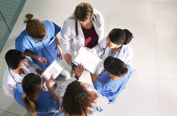 Finding ways to better the standards of healthcare High angle shot of a group of medical practitioners analyzing data in a hospital medical insurance data stock pictures, royalty-free photos & images