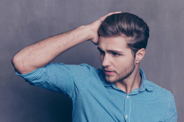 портрет молодого уверенного в себе красивого мужчины, прикасаясь к его волосам - men hairdresser human hair hairstyle стоковые фото и изображения