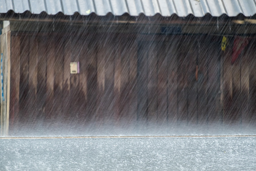 Heavy raining on asphalt road and wooden house