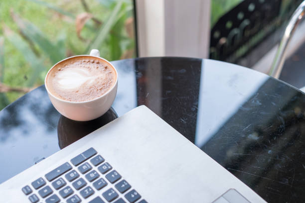 istock Laptop with latte hot coffee in white cup on glass table 944496590