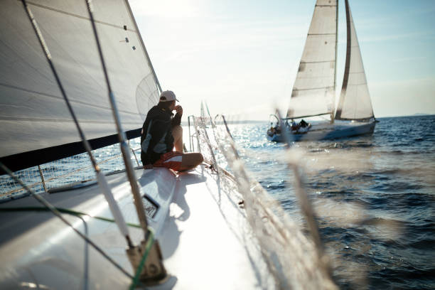 hombre guapo joven relajante en su velero - sailboat race fotografías e imágenes de stock