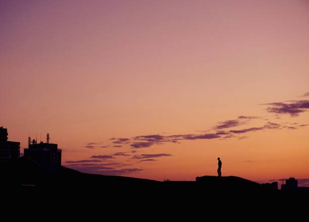 istock Silhouette people standing on hill at sunset time over city. 944498580