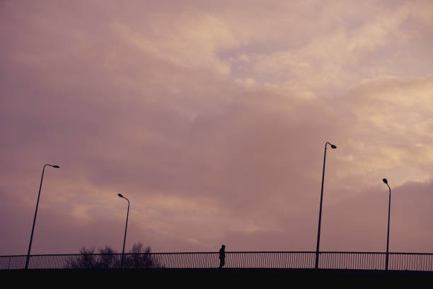 istock Silhouette person does on bridge at sunset time in city. 944498582