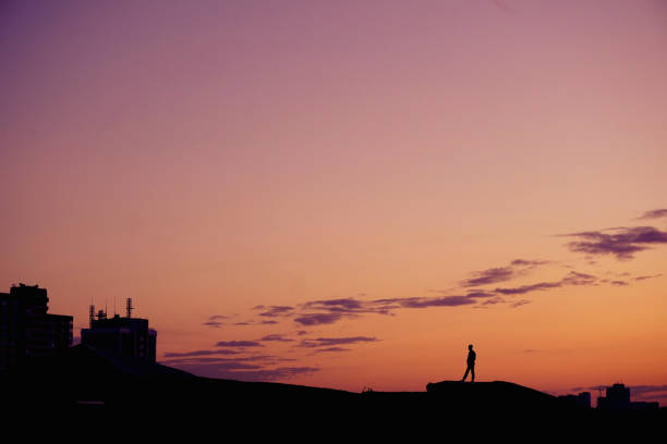istock Silhouette people standing on hill at sunset time over city. 944498604