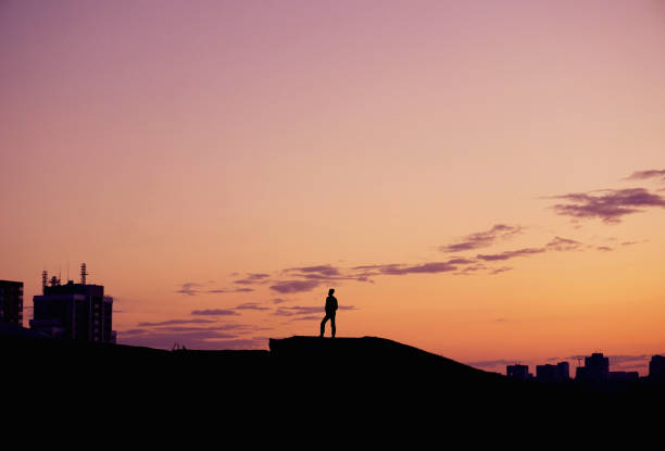 istock Silhouette people standing on hill at sunset time over city. 944498606