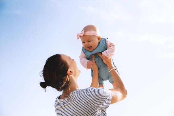 junge mutter wirft baby in den himmel, im freien. - baby or kind stock-fotos und bilder