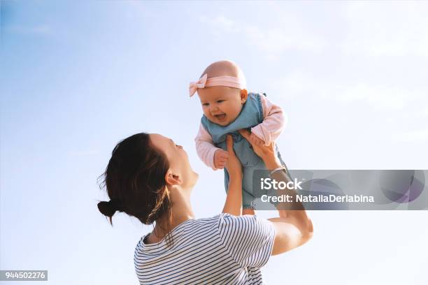 Foto de Jovem Mãe Joga Bebê No Céu Ao Ar Livre Do Verão e mais fotos de stock de Bebê - Bebê, Mãe, Criança