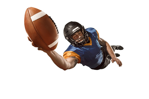 Active one american football player isolated on white background. Fit caucasian man in uniform with ball jumping over studio background in jump or motion. Human emotions and facial expressions concept