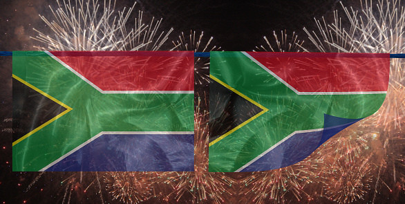 South African flag flies in a strong wind against a mostly clear summer sky.