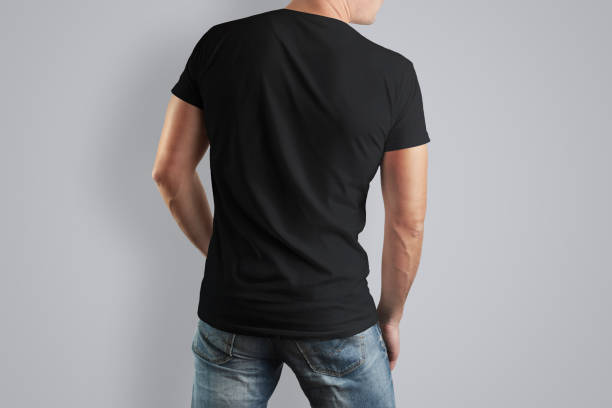 istock Back Mockup  black cotton T-shirt on a man posing on a gray background. 944506954