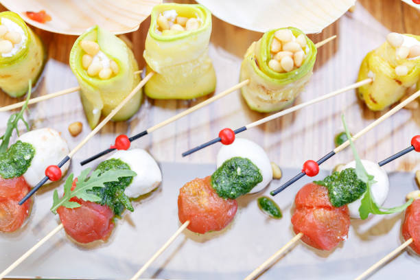 istock Zucchini rolls with pine nuts. Cherry tomatoes,mozzarella and Basil on skewers. . Pesto sauce. Tasty buffet table. Summer party outdoor. 944507246