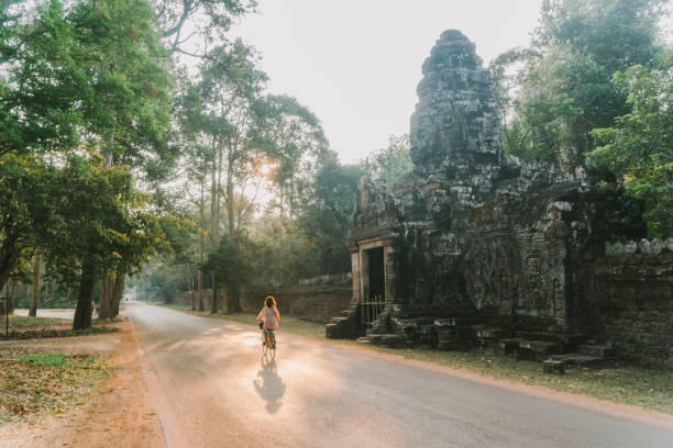 young caucasian woman riding  bicycle  in angkor wat - angkor wat imagens e fotografias de stock