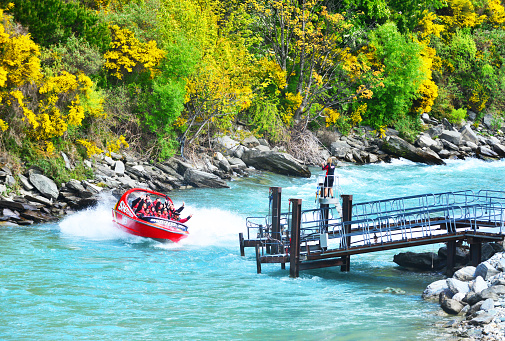 Tourists enjoy a high-speed boat ride on Queenstown's Shotover river in Queenstown, New Zealand. Queenstown is a popular alpine resort