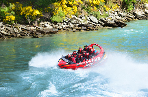 Tourists enjoy a high-speed boat ride on Queenstown's Shotover river in Queenstown, New Zealand. Queenstown is a popular alpine resort