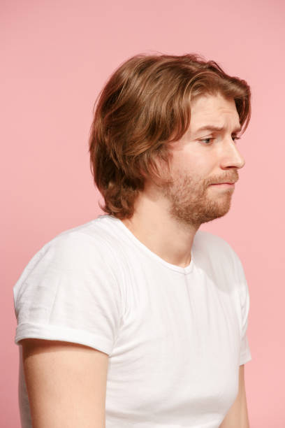 istock Let me think. Doubtful pensive man with thoughtful expression making choice against pink background 944518612