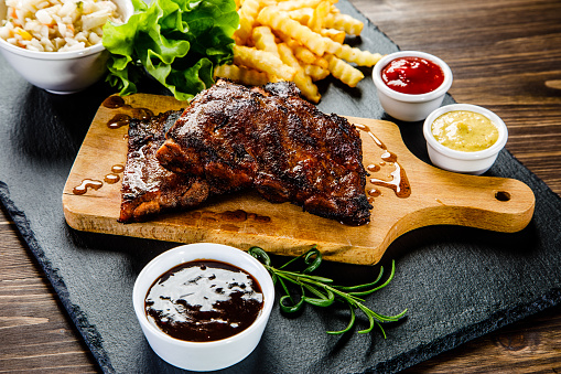 Grilled ribs, boiled potatoes and vegetables on wooden background