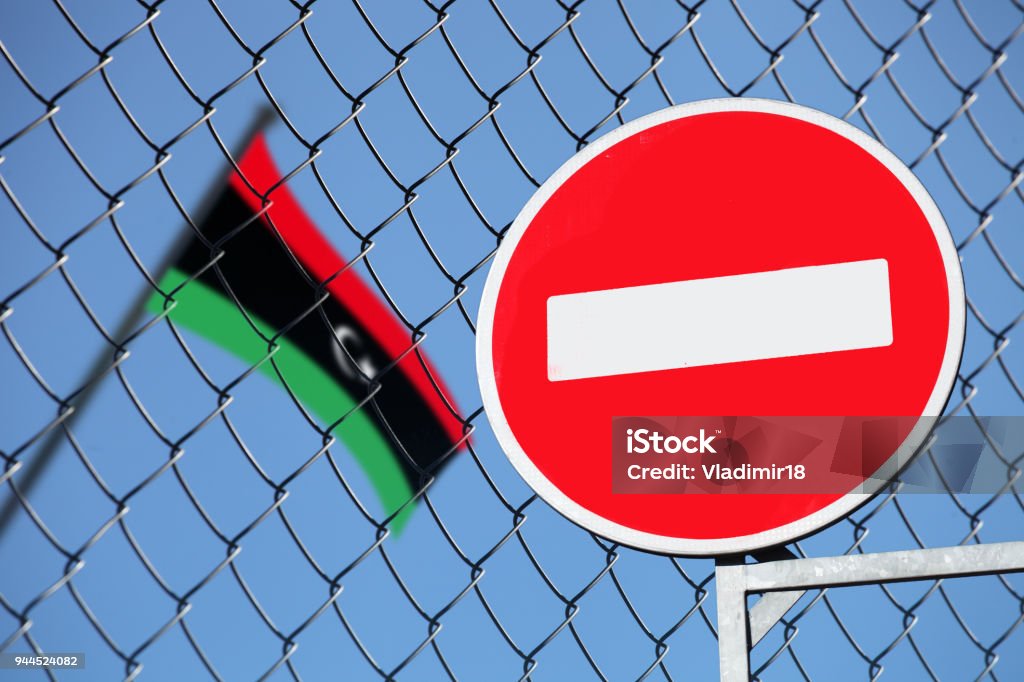 the flag of Libya behind the fence with the sign is forbidden the flag of Libya behind the fence Exclusion Stock Photo