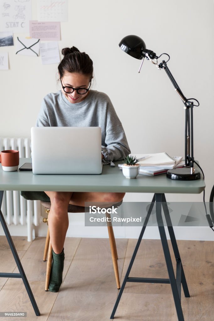 Frau arbeitet auf einem Laptop in ihrem Haus - Lizenzfrei Arbeiten von Zuhause Stock-Foto