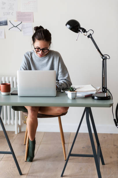 femme travaillant sur un ordinateur portable chez elle - simplicity using computer women computer equipment photos et images de collection